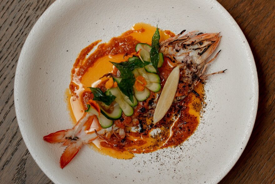 A top-down, close-up shot of a gourmet seafood dish served in a wide, shallow white bowl, resting on a table.