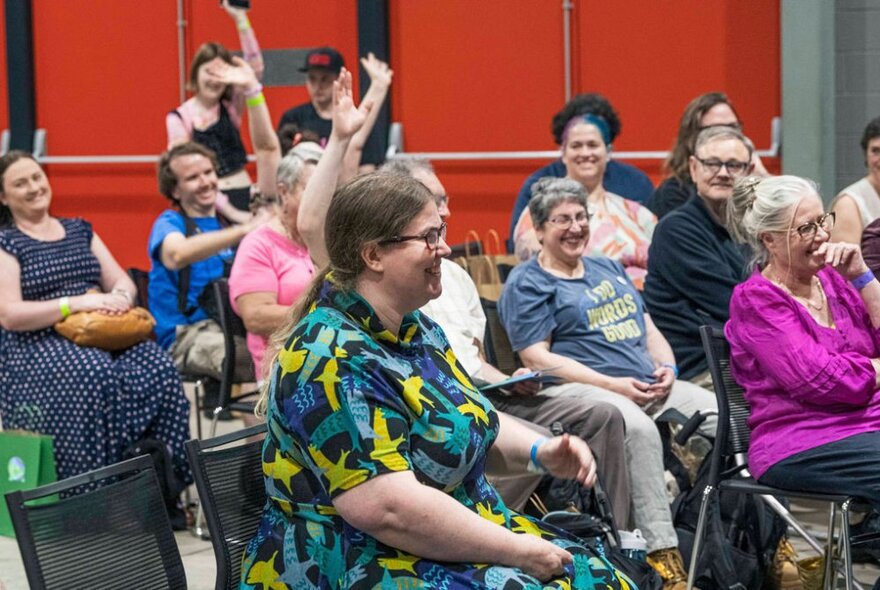 Audience members all smiling and laughing, some with hands in the air.