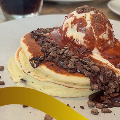 A plate of fluffy pancakes with ice-cream and chocolate over the top. 