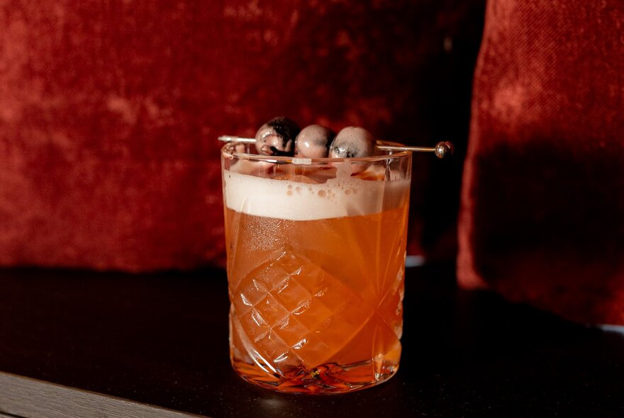 A frothy cocktail with olive garnishes.