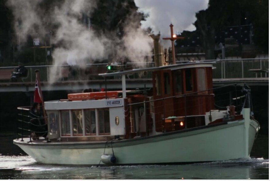 Dark image of a steam-powered boat chugging smoke on the river.