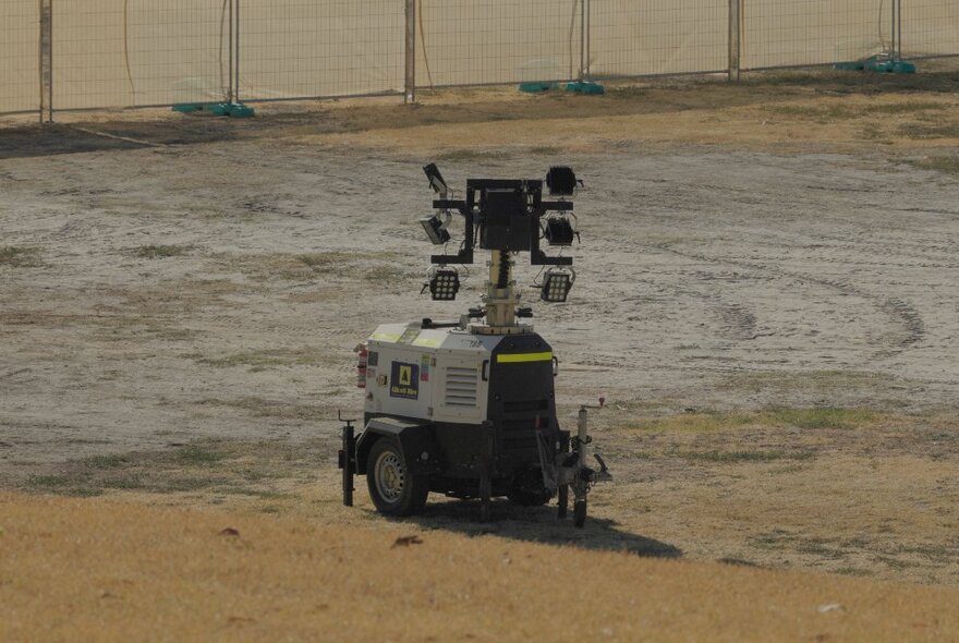 A small robotic vehicle with cameras attached to the top of it, moving around an area of sandy dirt.