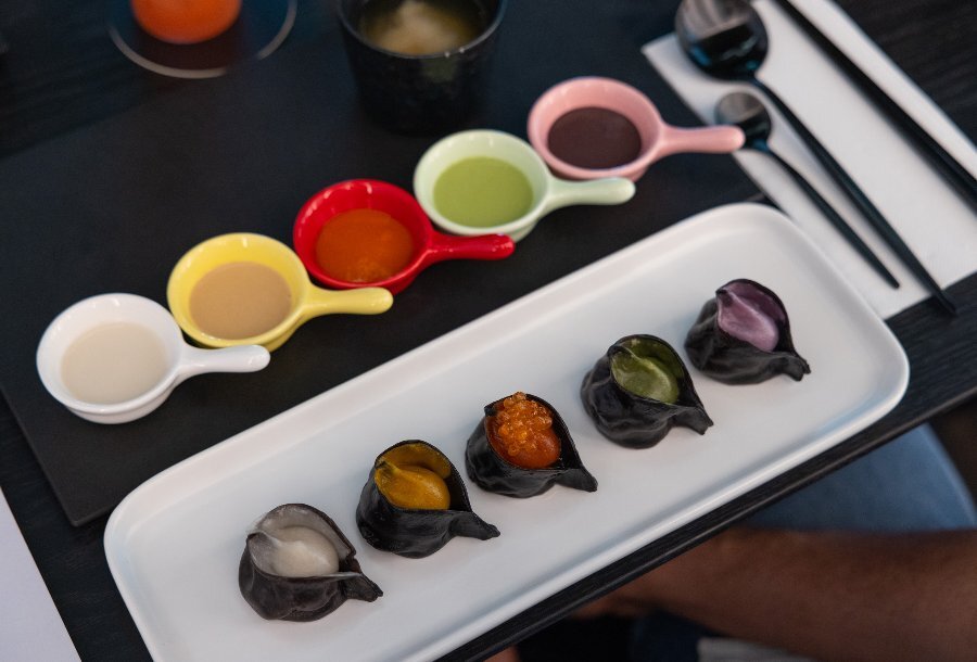 A colourful platter of dumplings and sauces. 
