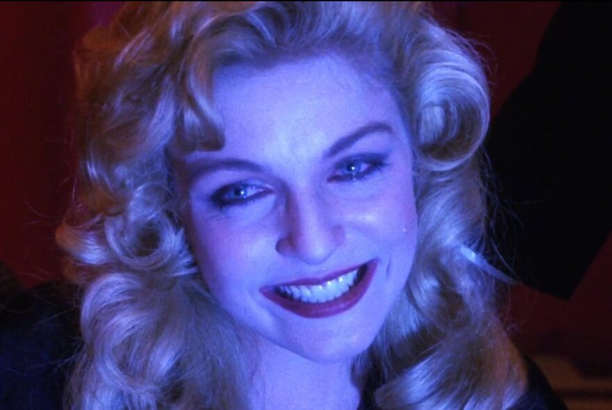 A smiling Laura Palmer with a blue light case on her face in a still image from the film Fire Walk With Me. 