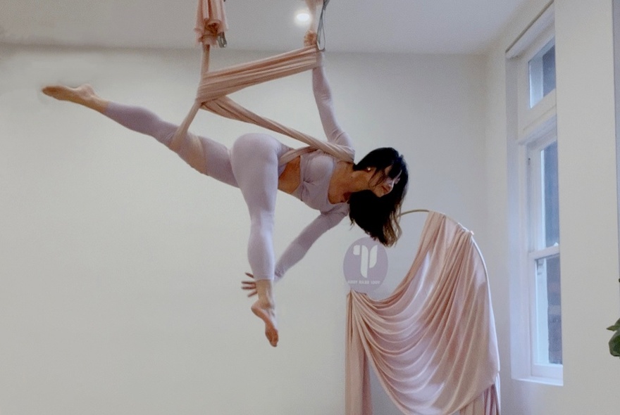 Yoga practitioner balancing from aerial robes.