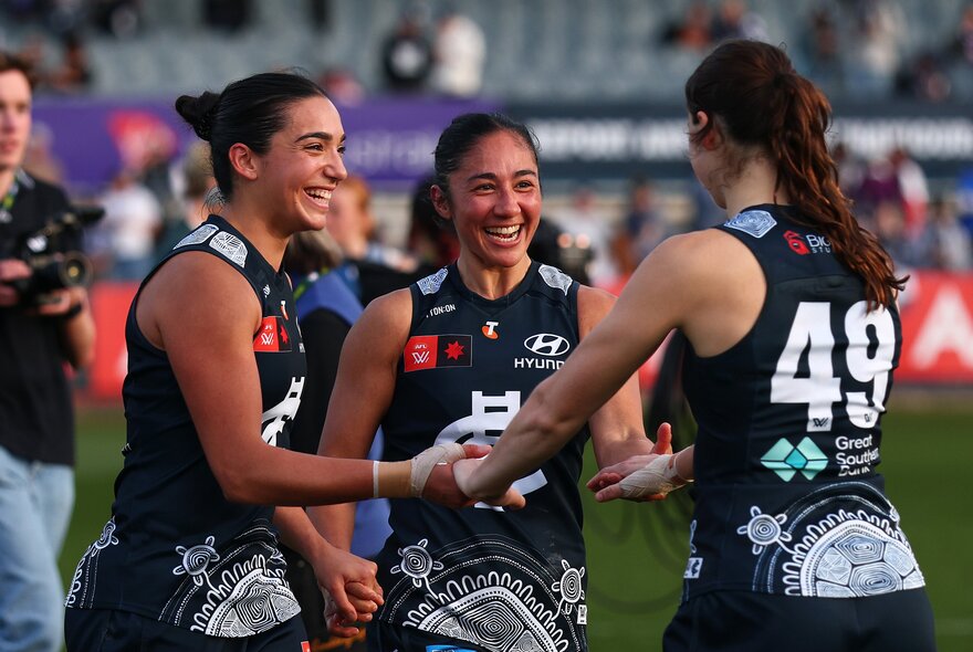 Carlton AFLW players happy on the football field. 