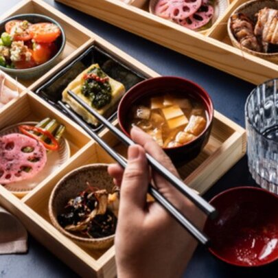 Someone eating from a beautiful bento box with chopsticks.