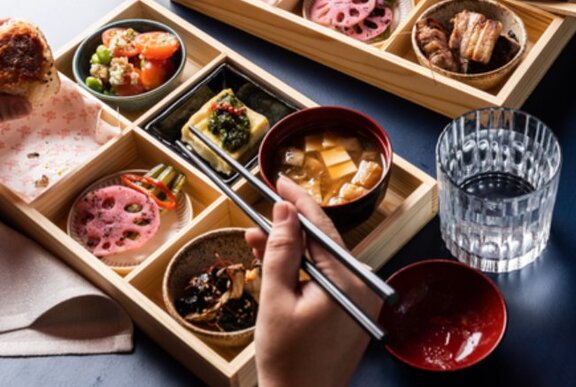 Someone eating from a beautiful bento box with chopsticks.