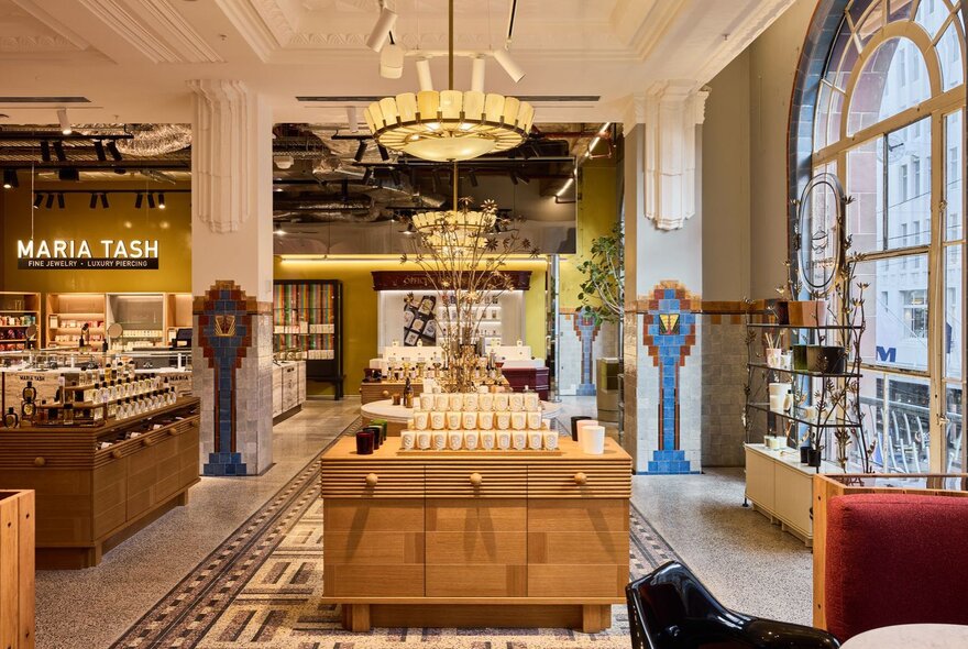Perfume counters in a beauty store with five large arched windows and tiled floors.
