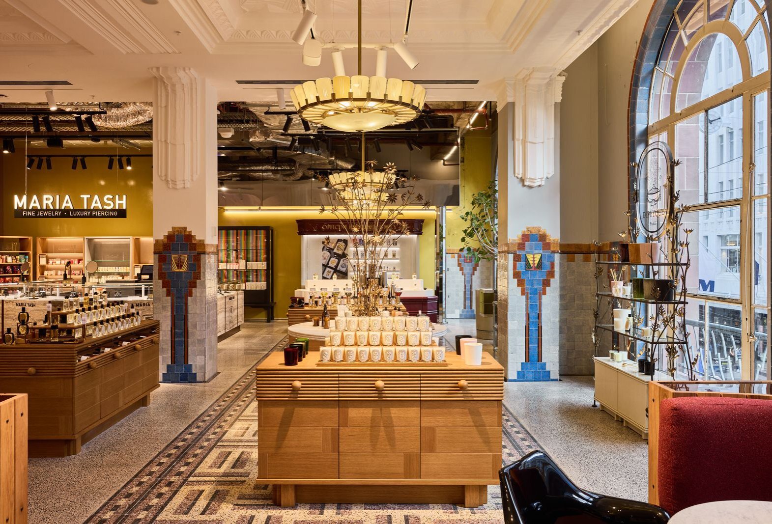 Perfume counters in a beauty store with five large arched windows and tiled floors.
