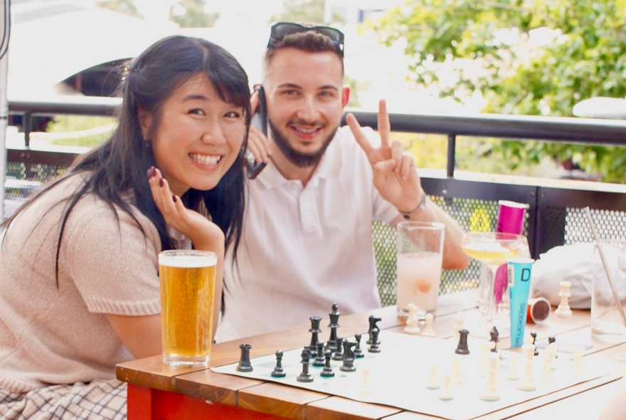 People playing chess outdoors at a table in a pub.