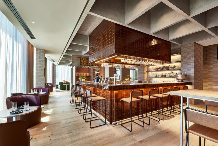 Restaurant interior with stools at bar in middle.