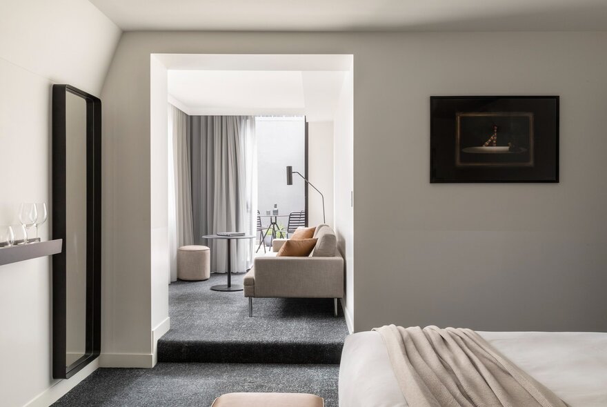A hotel suite at the Lancemore Crossley St hotel, with a lounge area in the rear and a bed in the foreground.
