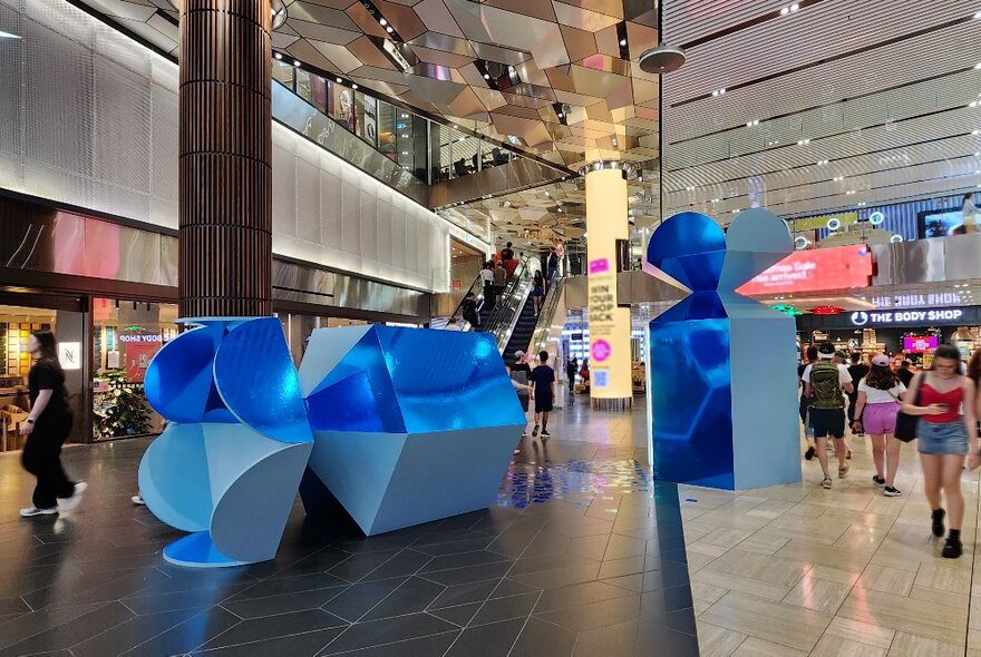 A large blue bon bon broken in two inside a shopping mall.