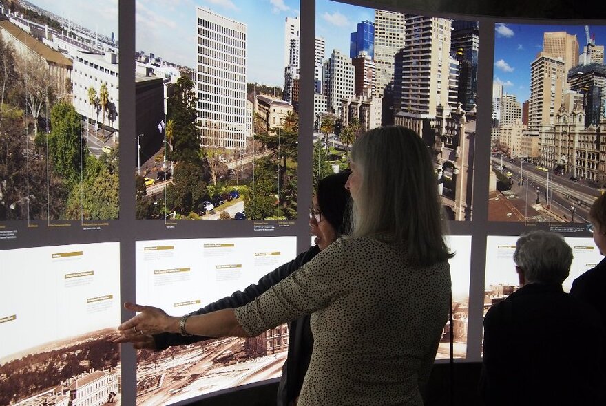 People in a room looking at a photographic display on a wall.