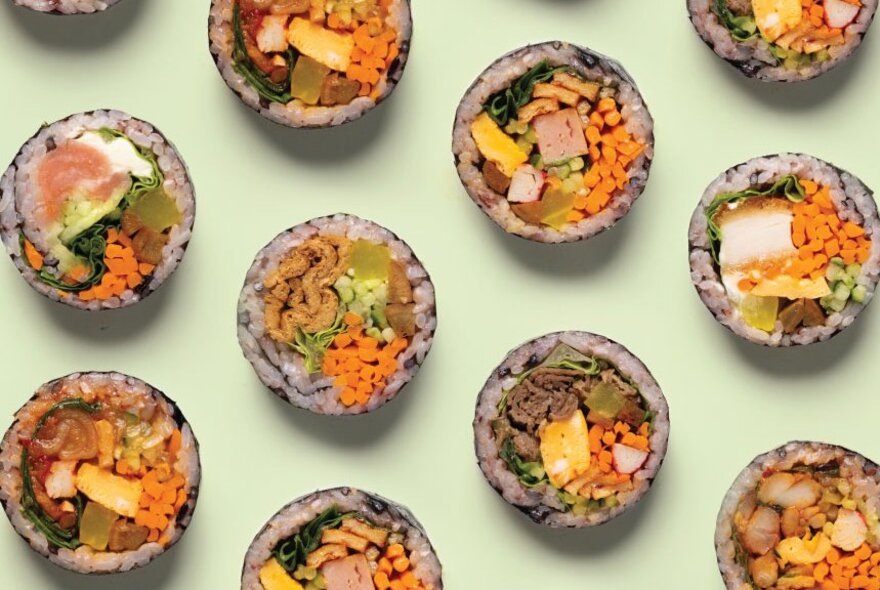 Slices of kimbap on a pale green background.