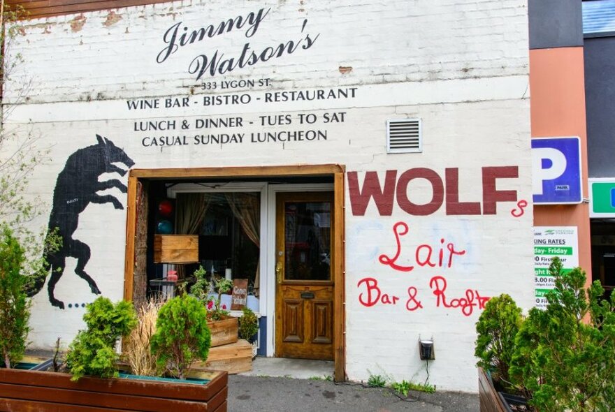 The exterior of a bar with a wolf on the wall.