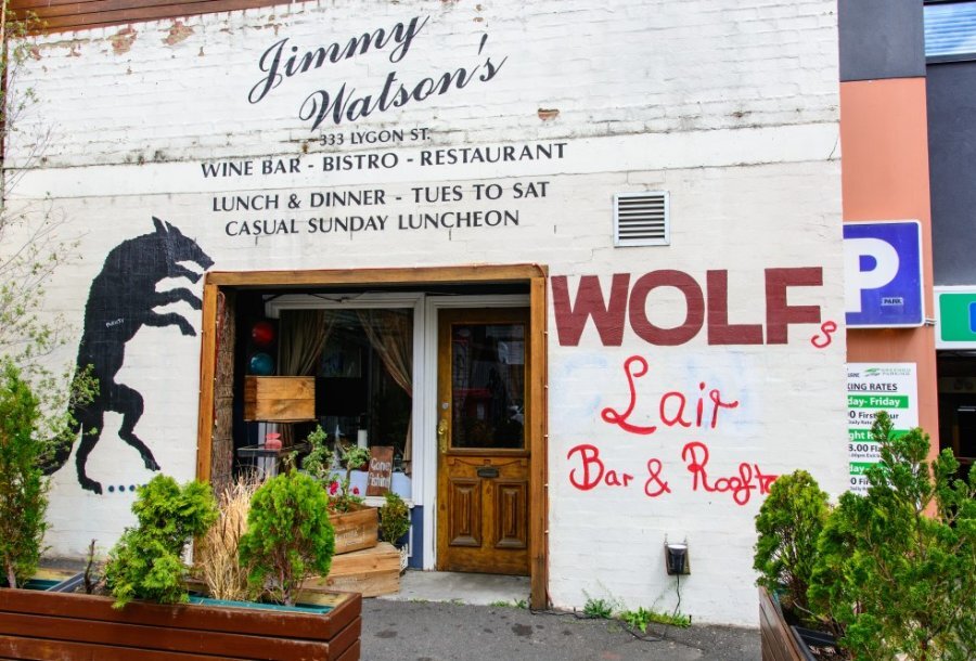 The exterior of a bar with a wolf illustration on the wall.