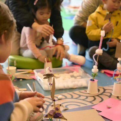 Children and their carers engaging in a creative craft workshop around a table at the State Library Victoria.