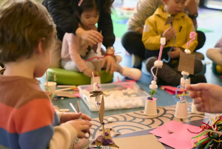 Children and their carers engaging in a creative craft workshop around a table at the State Library Victoria.