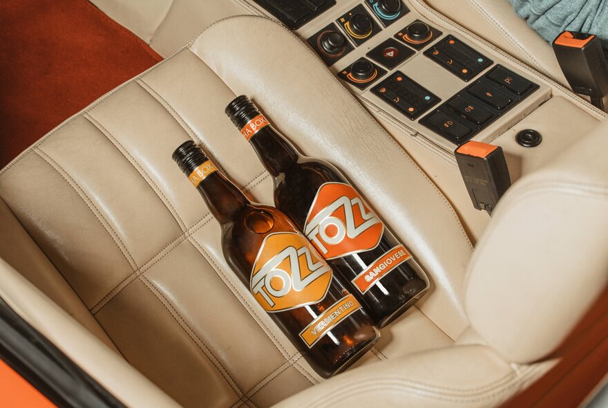 Bottles of wine resting in the beige passenger seat of a sports car.