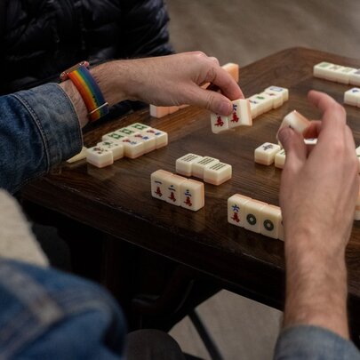 Hands playing a game of mahjong on a table.