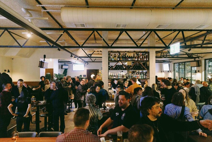 Interior of Springrock Public Bar with people standing around a central bar area.