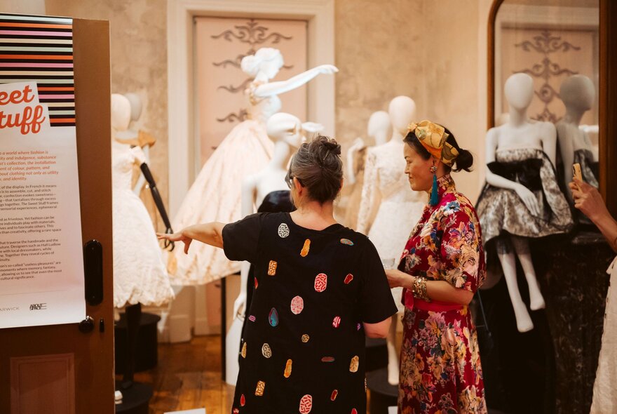 People looking at a fashion exhibition with white mannequins in the background. 
