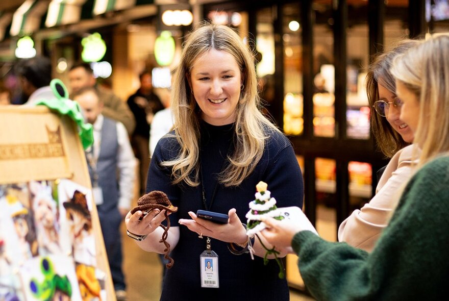 Three women shopping at a Chirstmas market, smiling.