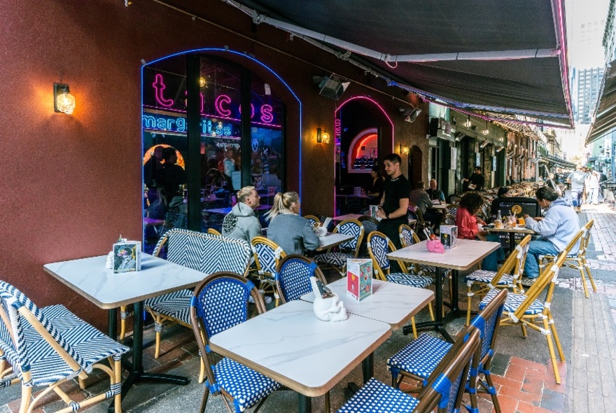 Tables set in a laneway under a large awning. 