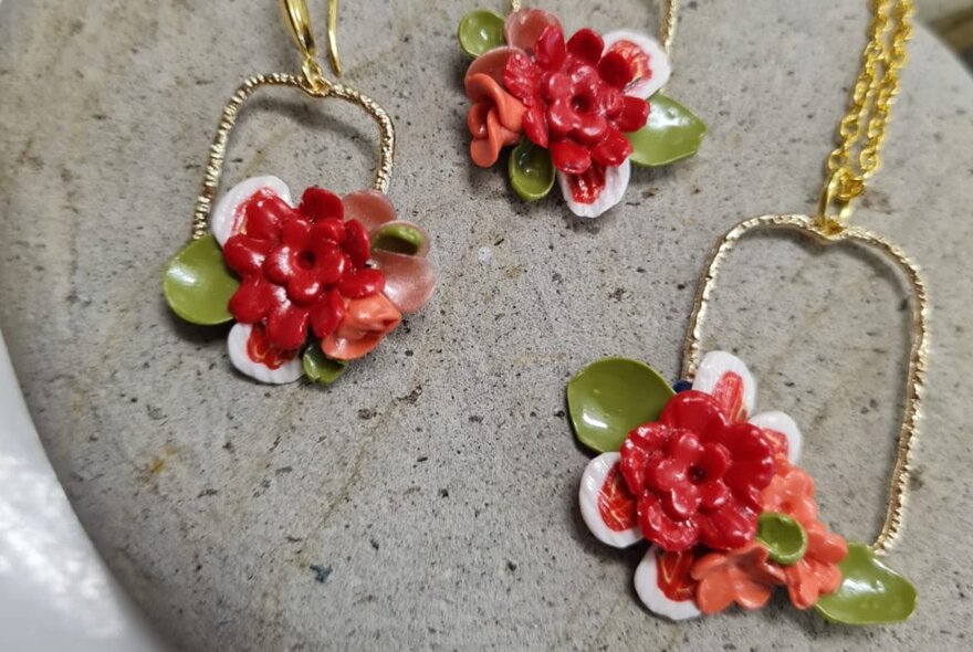 Earrings and a necklace with a red and green floral design, made from polymer clay.