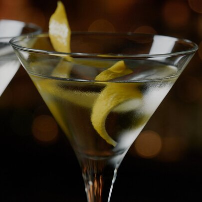 The top half of a martini cocktail in a martini glass with a twist of lemon rind.