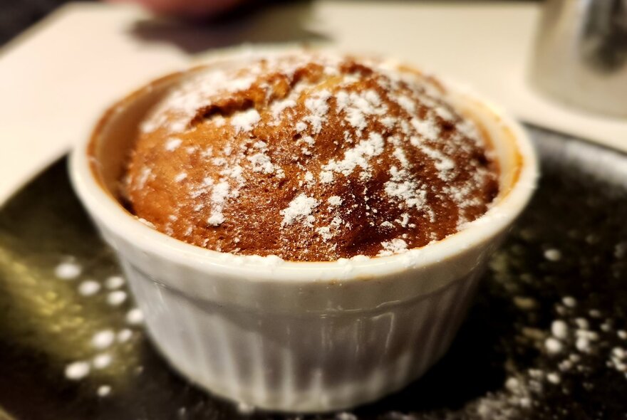 A sugar-sprinkled souffle in a white porcelain dish.