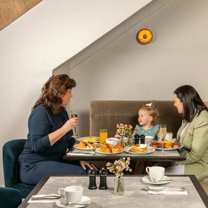 Two women and a child enjoying a breakfast, seated at a restaurant table.