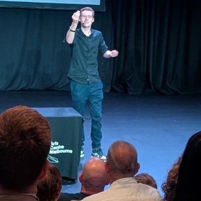 A magician standing on a stage performing in front of an audience.