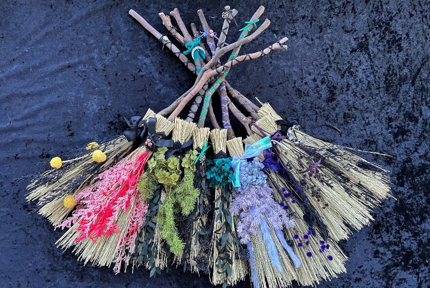Small handcrafted brooms made from straw and other natural elements.