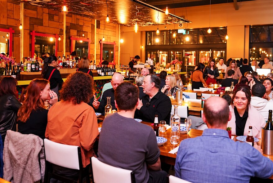 The interior of a large restaurant with every table filled with patrons.