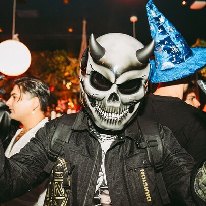 Person dressed as a Halloween devil with horns and skull at a themed party.