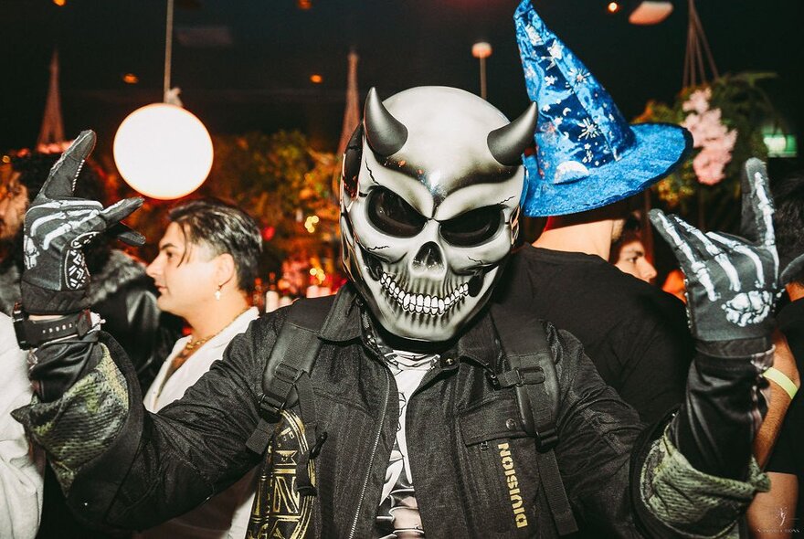 Person dressed as a Halloween devil with horns and skull at a themed party.