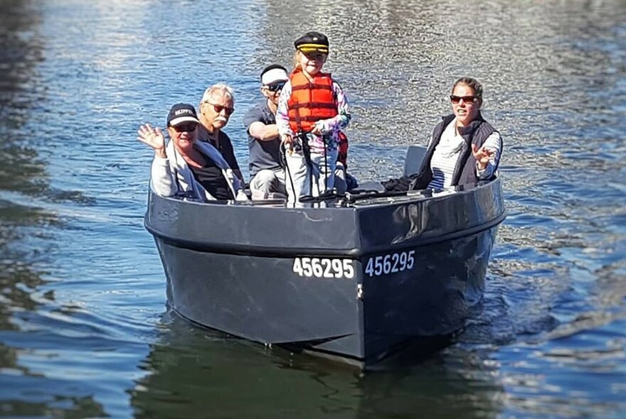 A family having fun driving a small boat along the Yarra River.