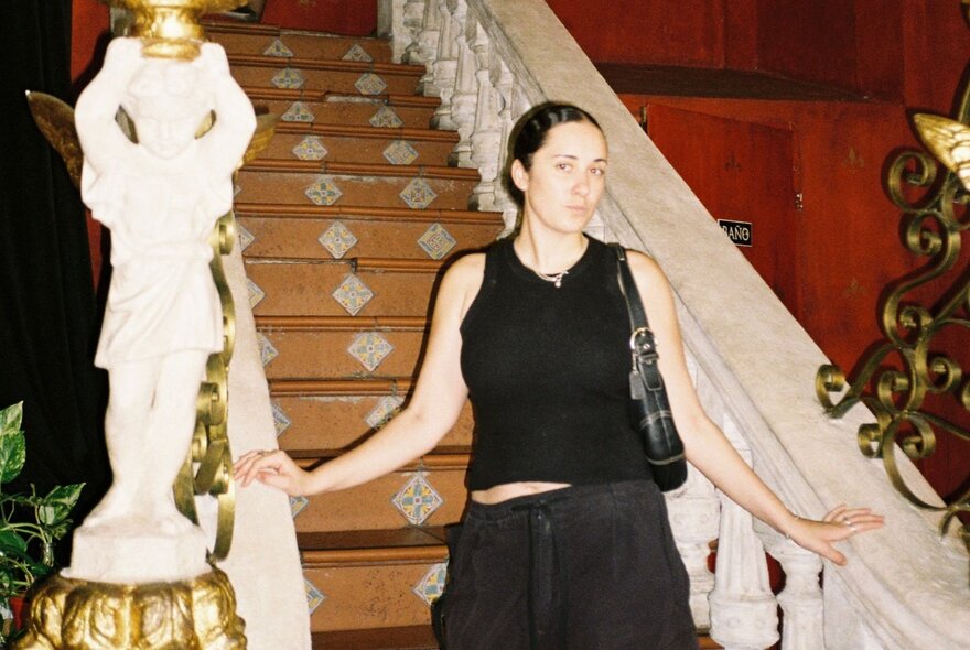 A person standing on an ornate staircase with patterned steps and intricate railings.