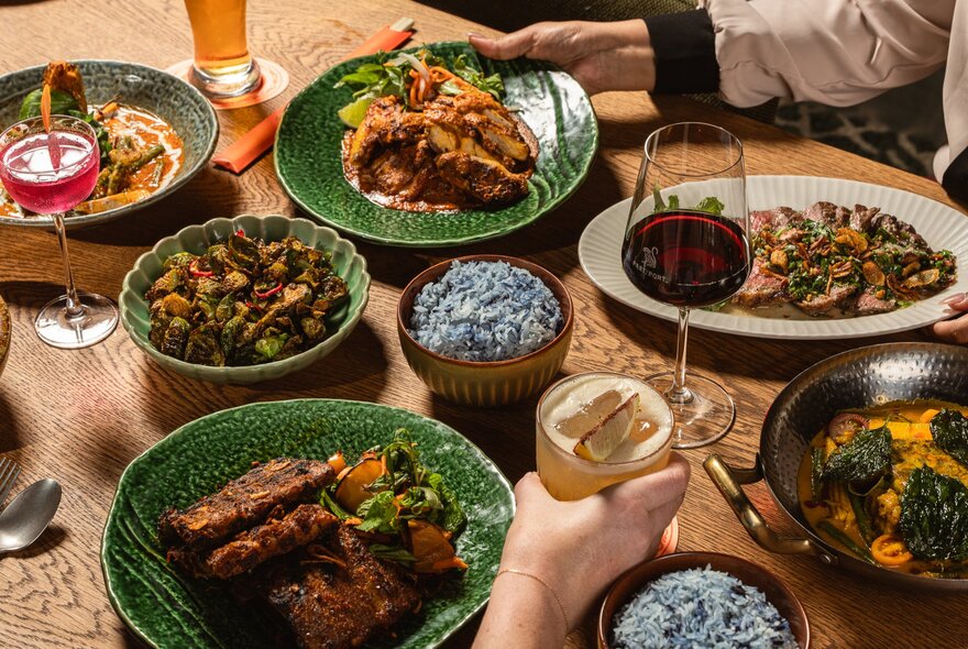Array of Southeast Asian dishes and drinks on a table.
