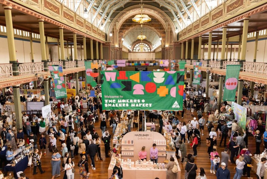 The interior of the Royal Exhibition Buiding during the Makers and Shakers Market, with crowds of people milling around the stalls.