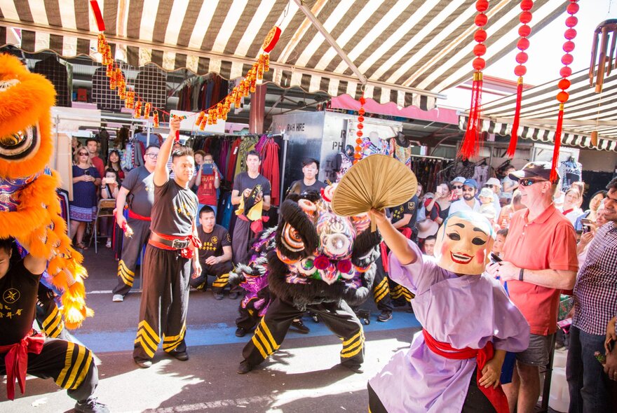 Lion dance performers under the awnings at the market.