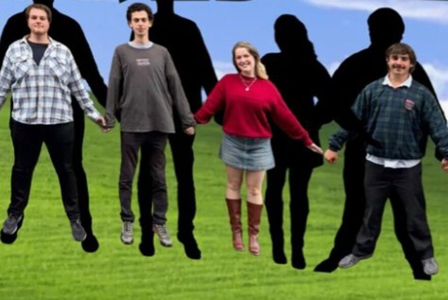 Four comedians holding hands, jumping into the air on green grass.