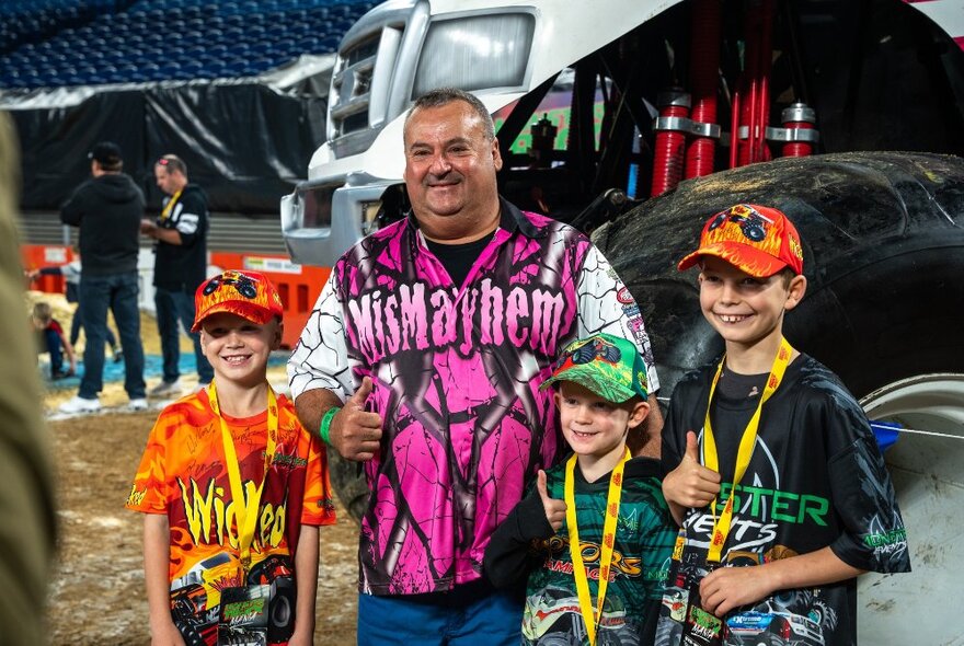 Kids posing with a man in front of a monster truck. 