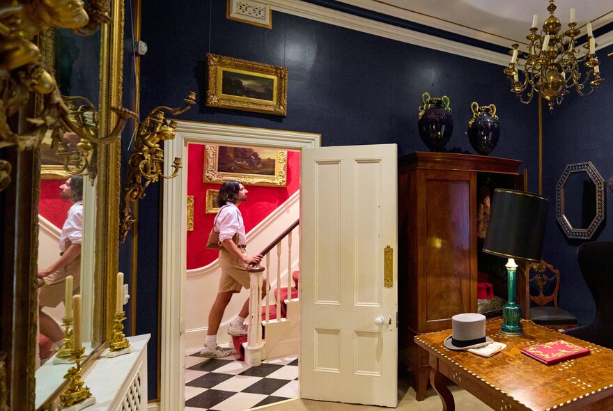 A person walking up the stairs in an ornately decorated home.