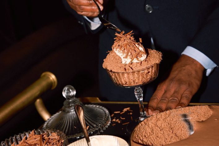 A chocolate mousse served in a stemmed glass with cream.