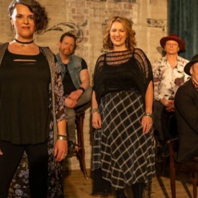 A six-piece band posed for a photo in a room, led by vocalist Lisa Mio in the foreground, and accompanied by the musical ensemble Wild Dreamers.