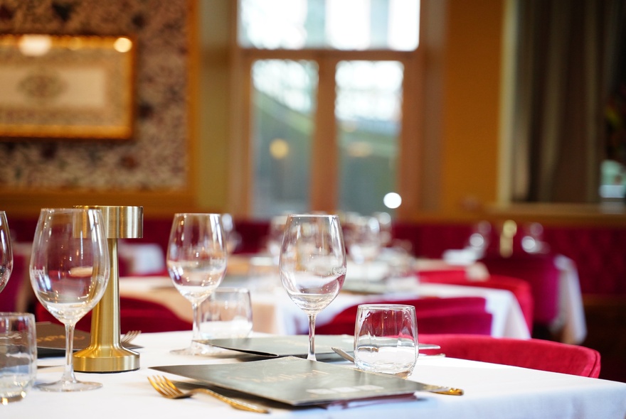 Table set for dining with cutlery, glasses and menus.